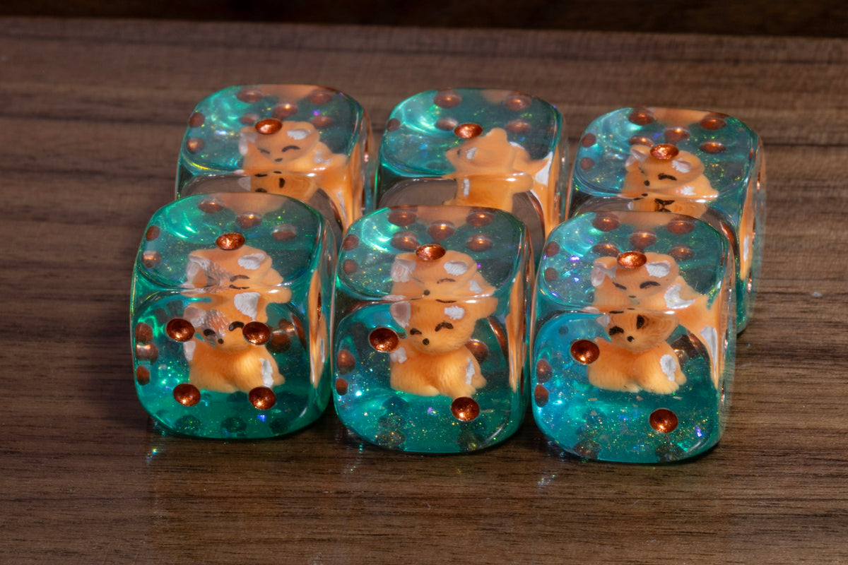 Fox's Cunning PIP D6 dice – fox cub figurines in clear resin on a teal glitter layer with copper pips