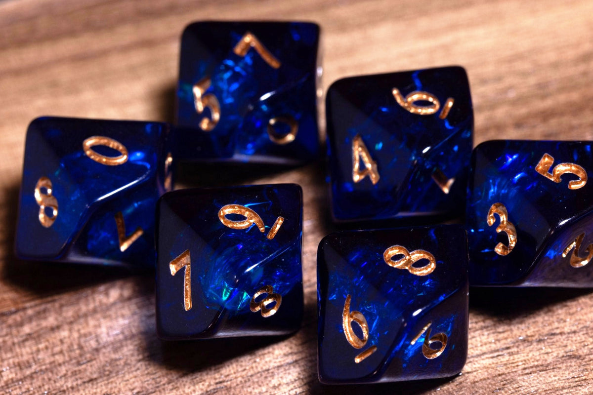 Six Cobalt Opal D10 dice, deep blue resin with holographic foil and gold numbers, on wood