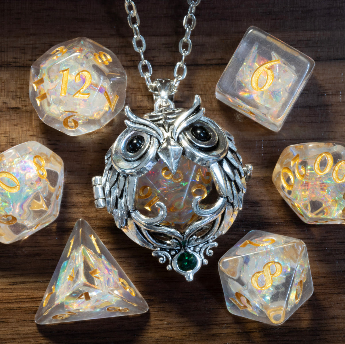 Owl pendant in a silver finish holding a Sacred Opal D20, beside the Sacred Opal dice set on wood