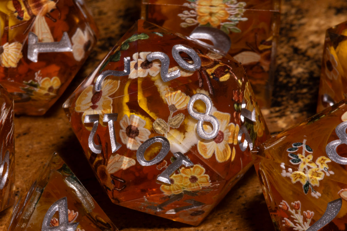 Honey Meadow Amber sharp edge dice close-up showing the bee and wildflower pattern